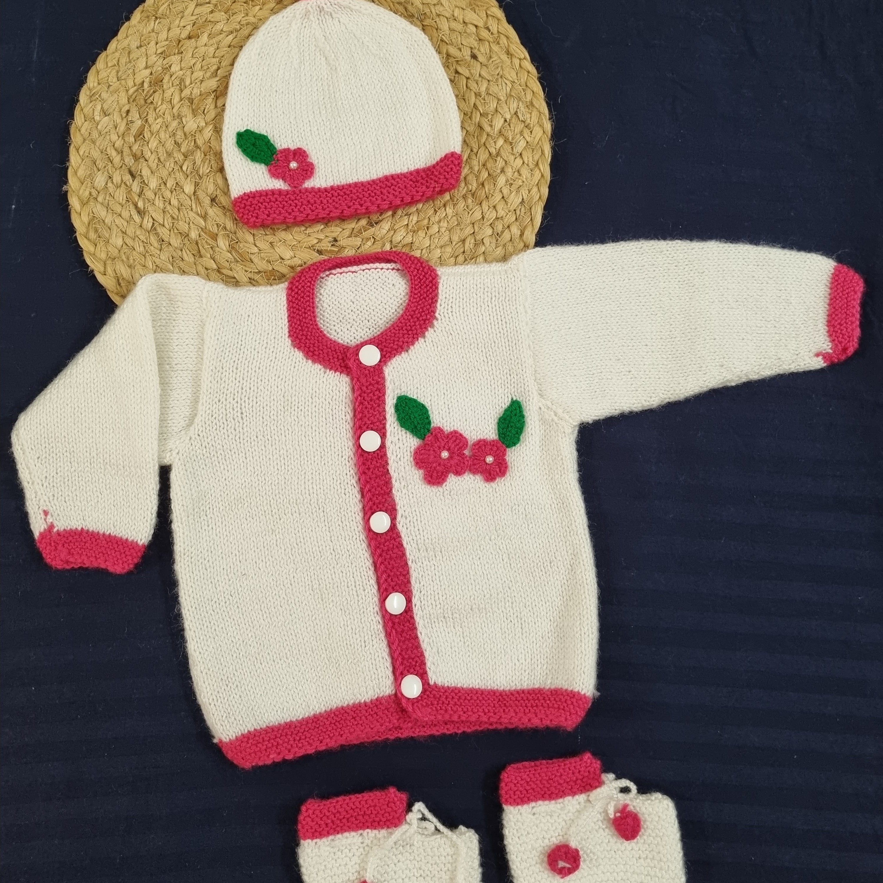 Knitted baby outfit with hat, bib, and booties on a dark background